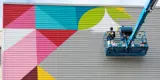 Large mural being created on the side of a building