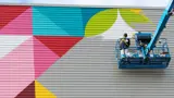 Large mural being created on the side of a building