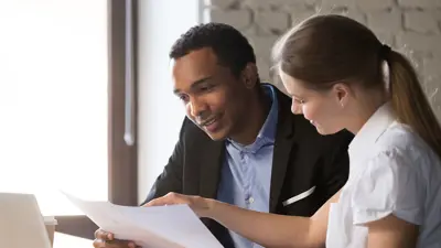 A man and woman checking paper and a laptop