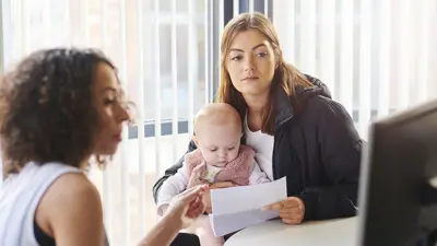 Woman and babie in a office talking to another woman while looking at a computer screen