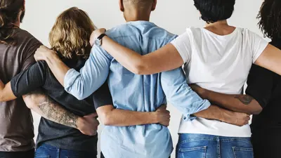 Five people with the backs to the camera holding each other shoulder to shoulder