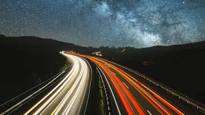 A night image of a road with blurred traffic lights