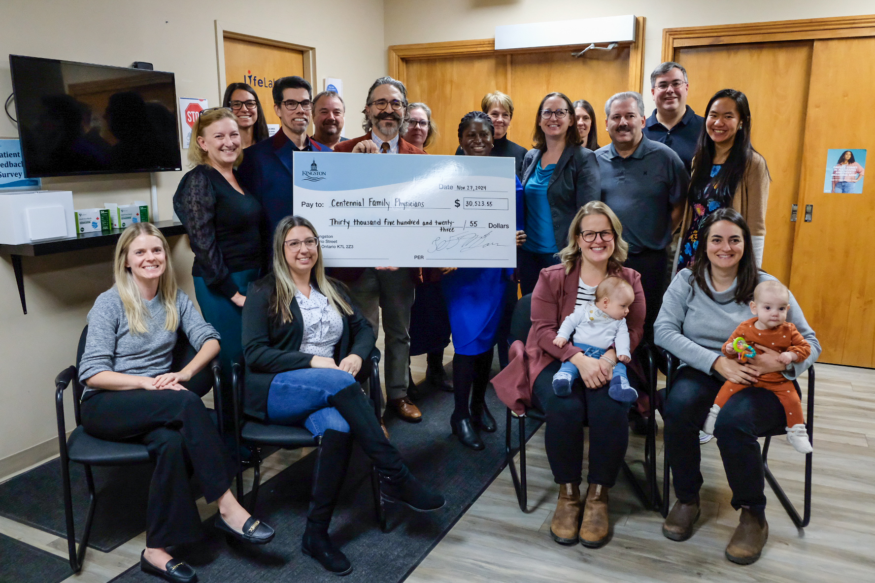 Team members of Centennial Family Physicians gathered in the clinic around a large City of Kingston cheque for $30,523.55.