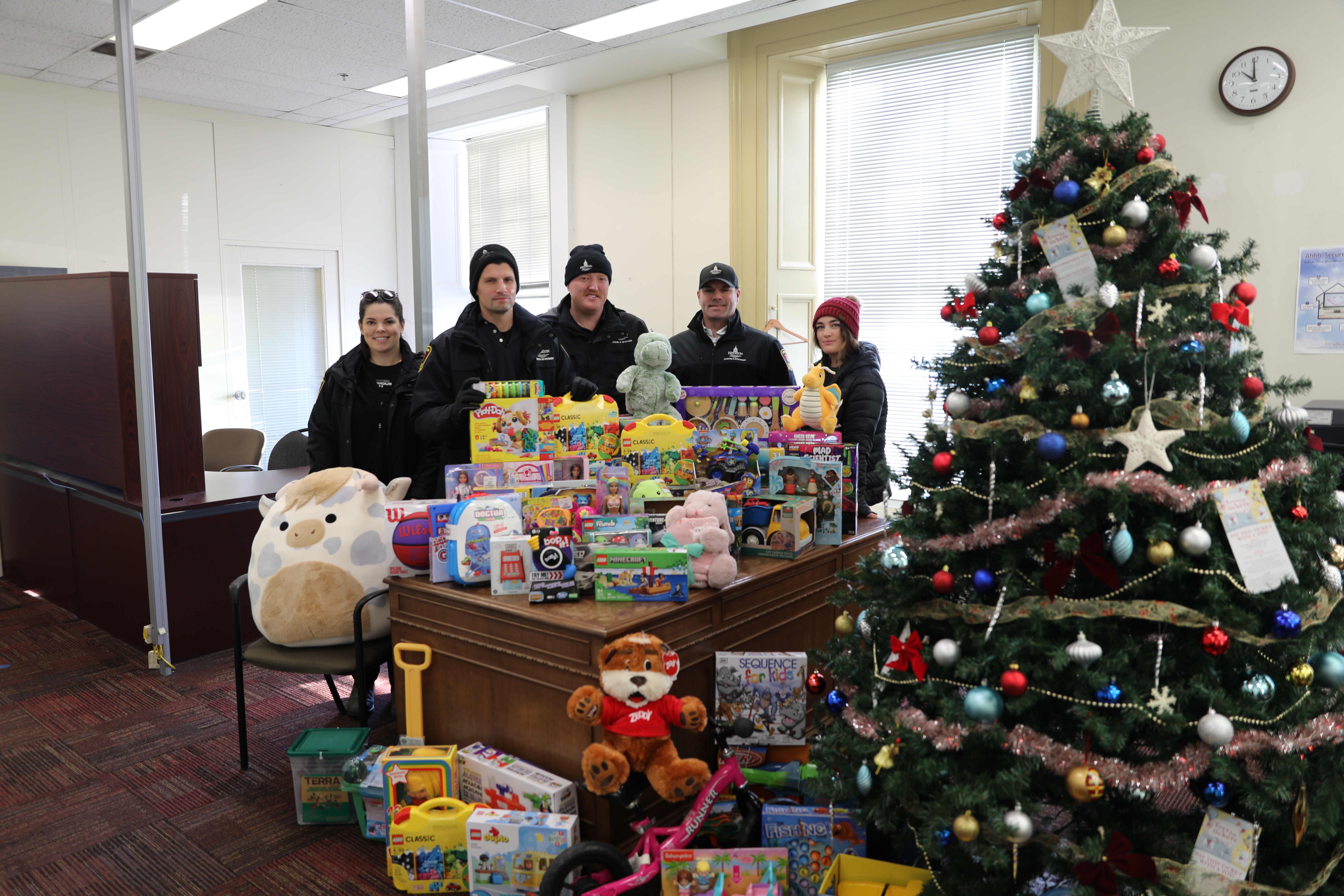 Members of the Parking Enforcement team standing beside a display of toys donated during the Toys for Tickets campaign.