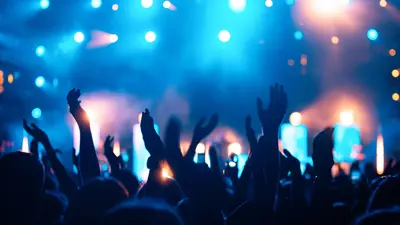 A concert crowd with hands in the air and bright lights