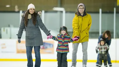 A family of a man, woman and child skating inside in a rink