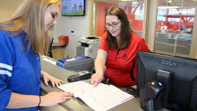 City worker showing resident a list of programs at the front desk