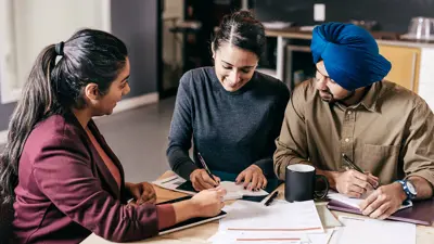 Group of people sitting at a table completing paperwork together