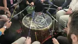 Multiple people drumming on an indigenous drum