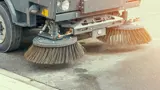 A close up of a street sweeping vehicle brushes